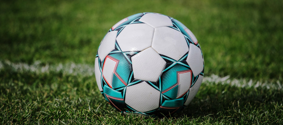 White teal soccer ball with geometric pattern, black stitching, red accents