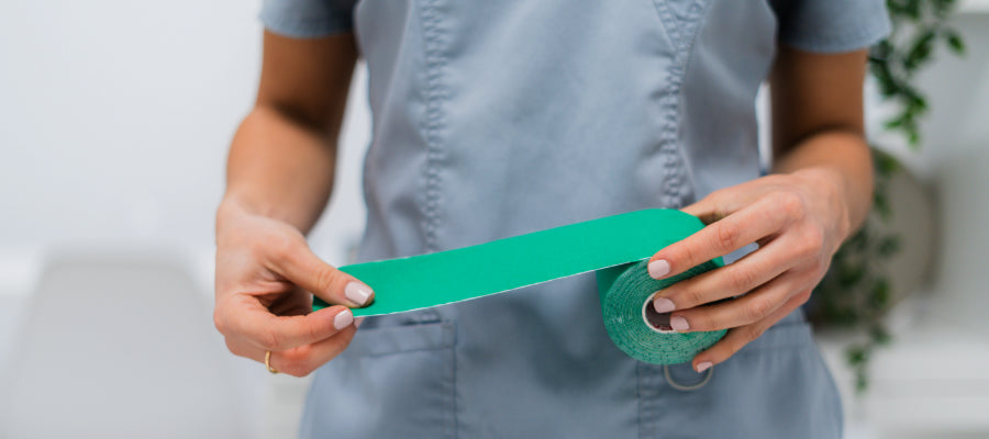 Hands holding green kinesiology tape roll from Locked In Tape